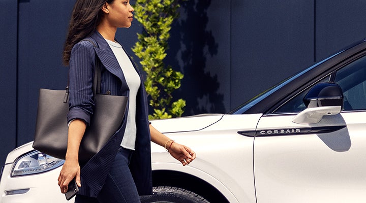 A woman approaches a 2024 Lincoln Corsair® SUV while holding a smartphone. | Vista Lincoln Woodland Hills in Woodland Hills CA